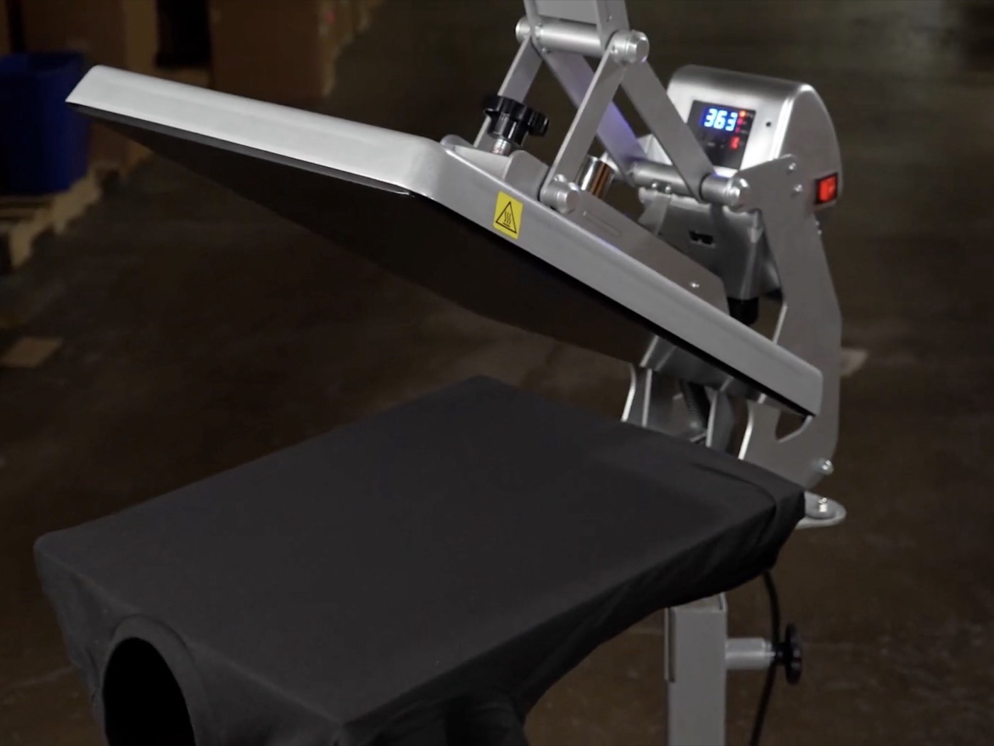 Clamshell heat press standing open at 363 degrees over a black shirt laid on the platen
